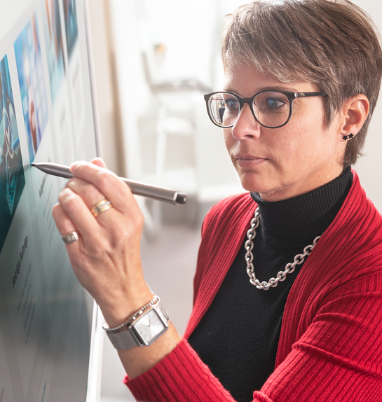 Eine IT-Spezialistin schreibt auf den Bildschirm in einem Meeting